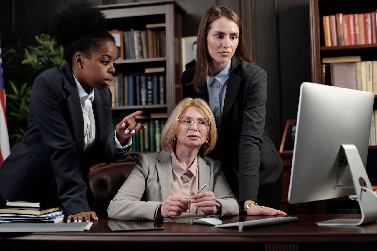 A diverse business team collaborating in a modern office setting around a computer.